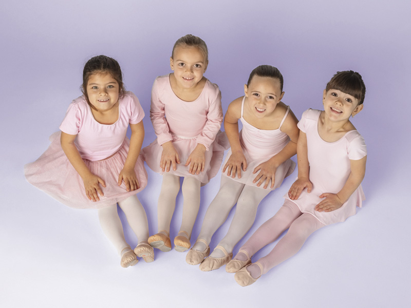 Ottawa Dance Centre School - Recreational Lower School - Four young dancers sitting with toes pointed wearing pink leotards and skirts